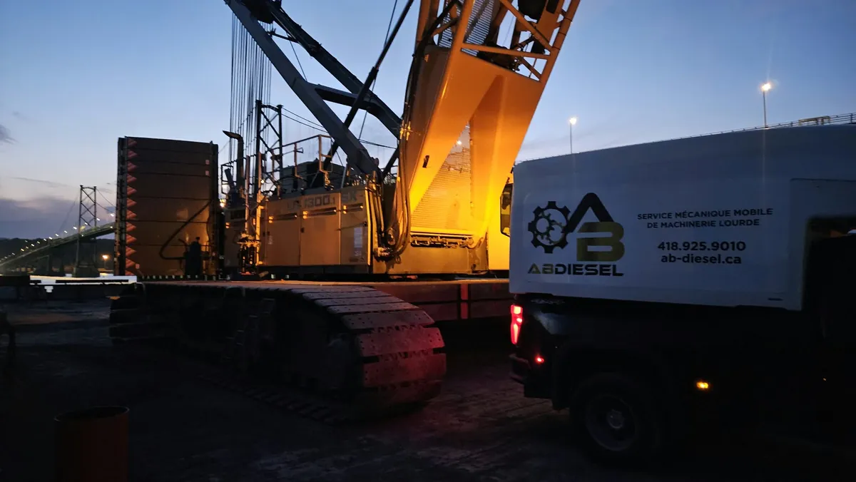 Camion AB Diesel près d’une grue sur chenilles au crépuscule